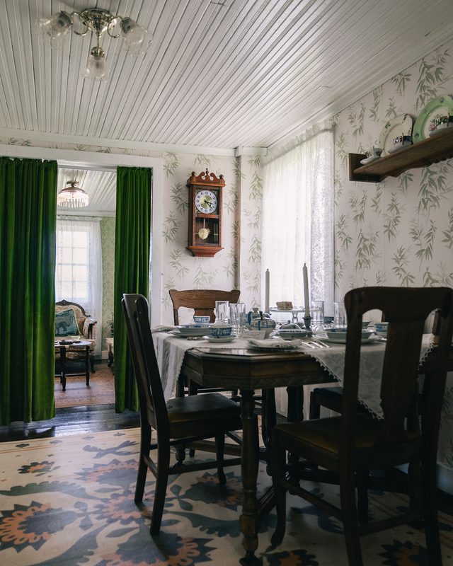 Dining room with delicate green bamboo-leaf wallpaper and antique furnishings