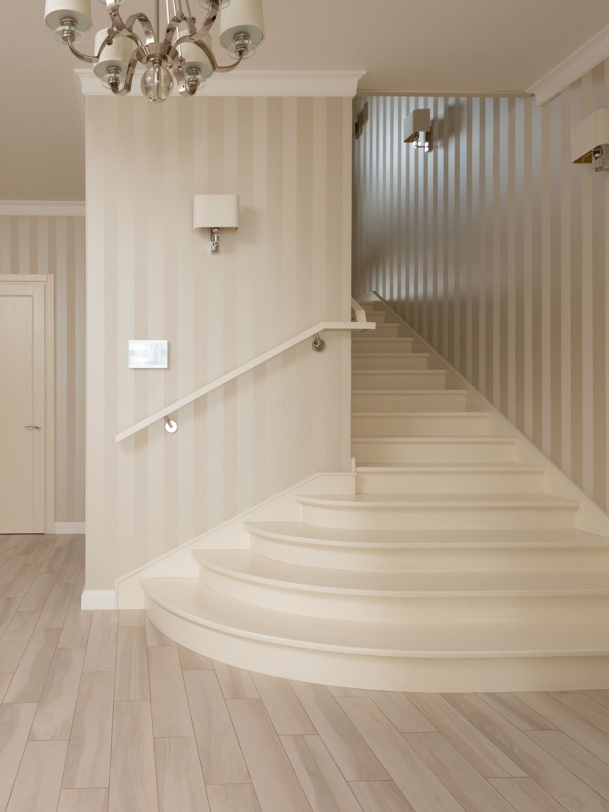 Elegant home foyer with warm sandstone striped wallpaper and a sweeping curved staircase