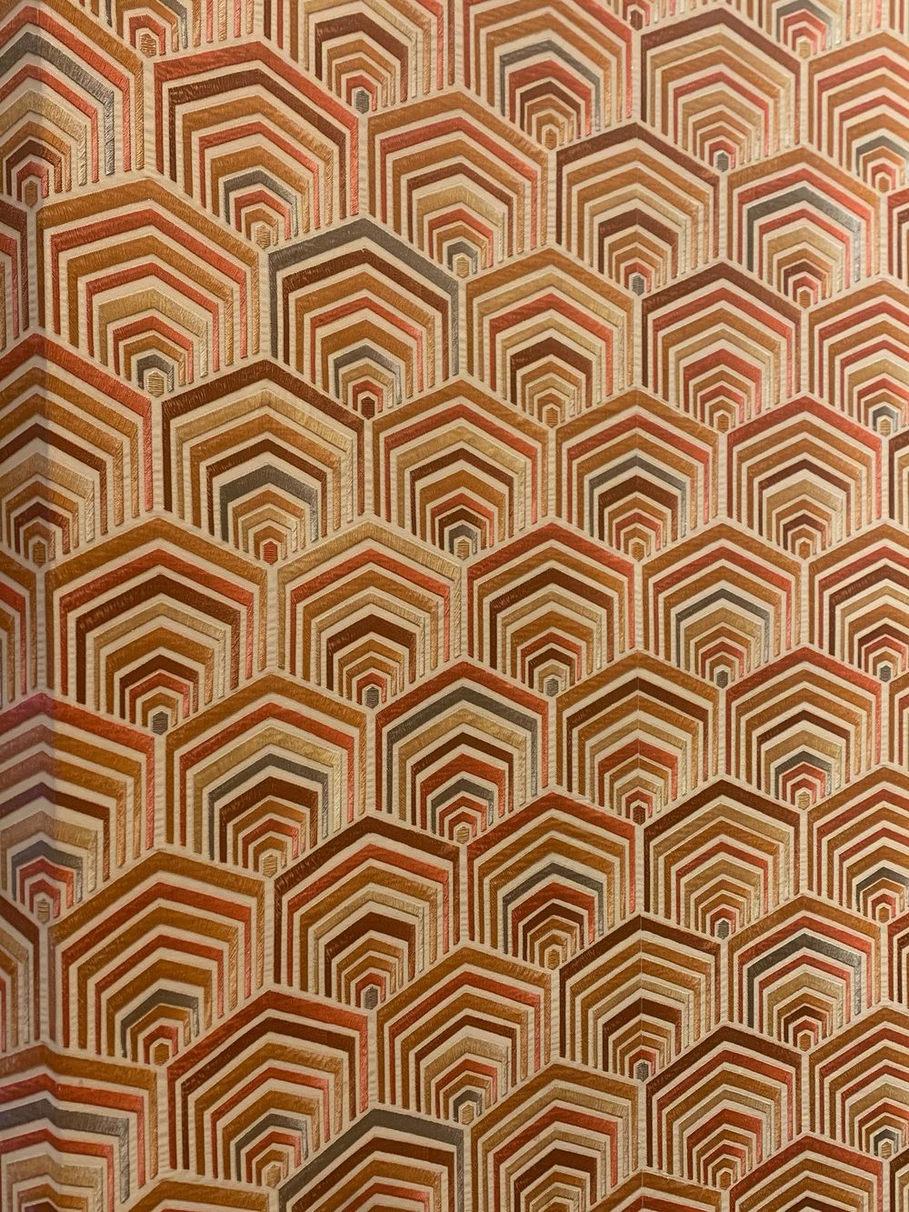 Close view of a warm terracotta and ochre geometric wallpaper pattern